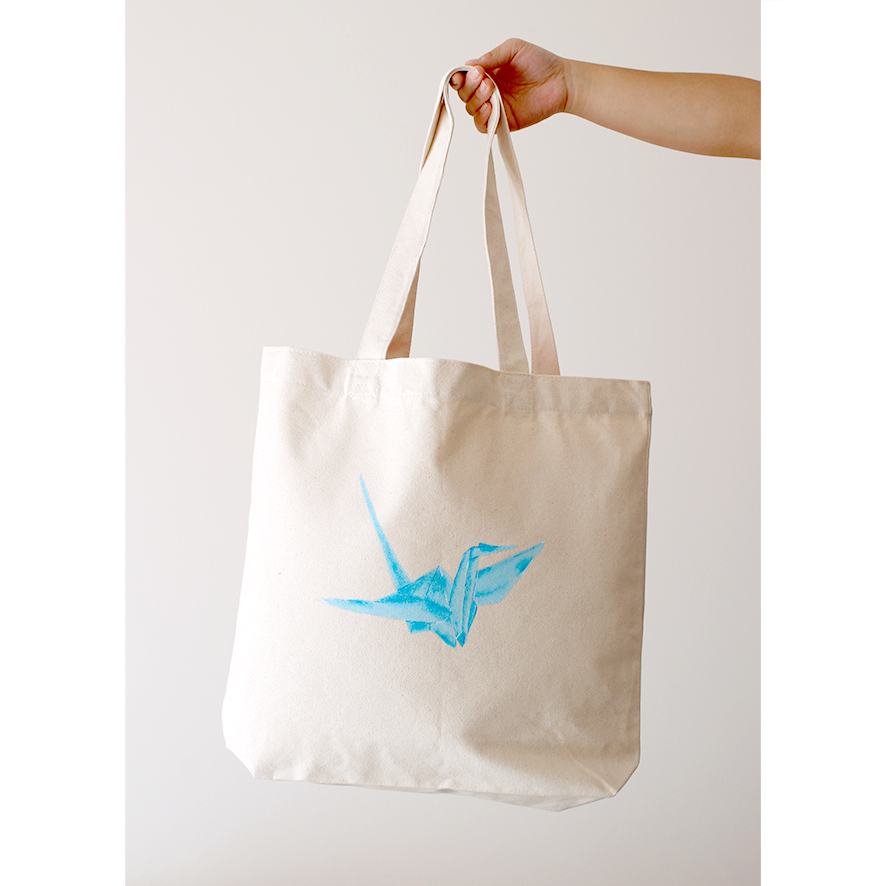 Hand-painted blue origami crane on a natural cotton canvas bag
