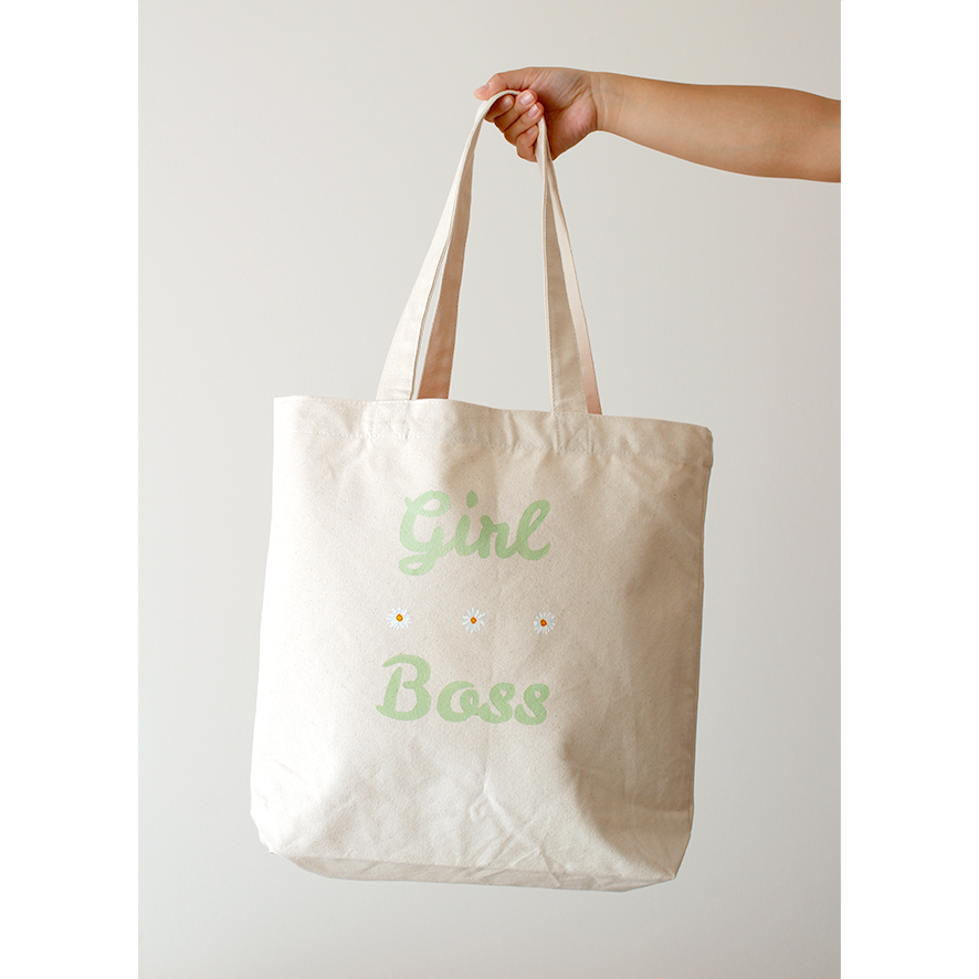 Green "girl boss" printed on a cotton canvas bag with delicate white daisies