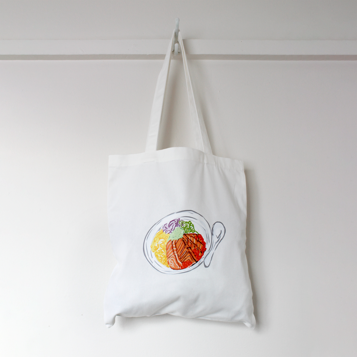 White tote bag with a colorful design of a chirashi bowl on a white background
