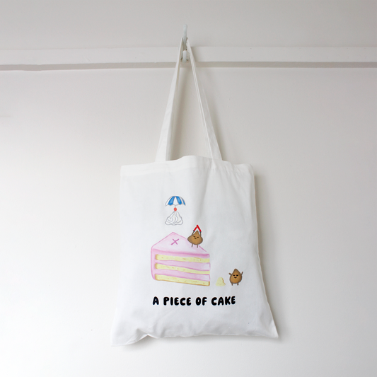 White tote bag with cake illustration and text 'A Piece of Cake' on a white background