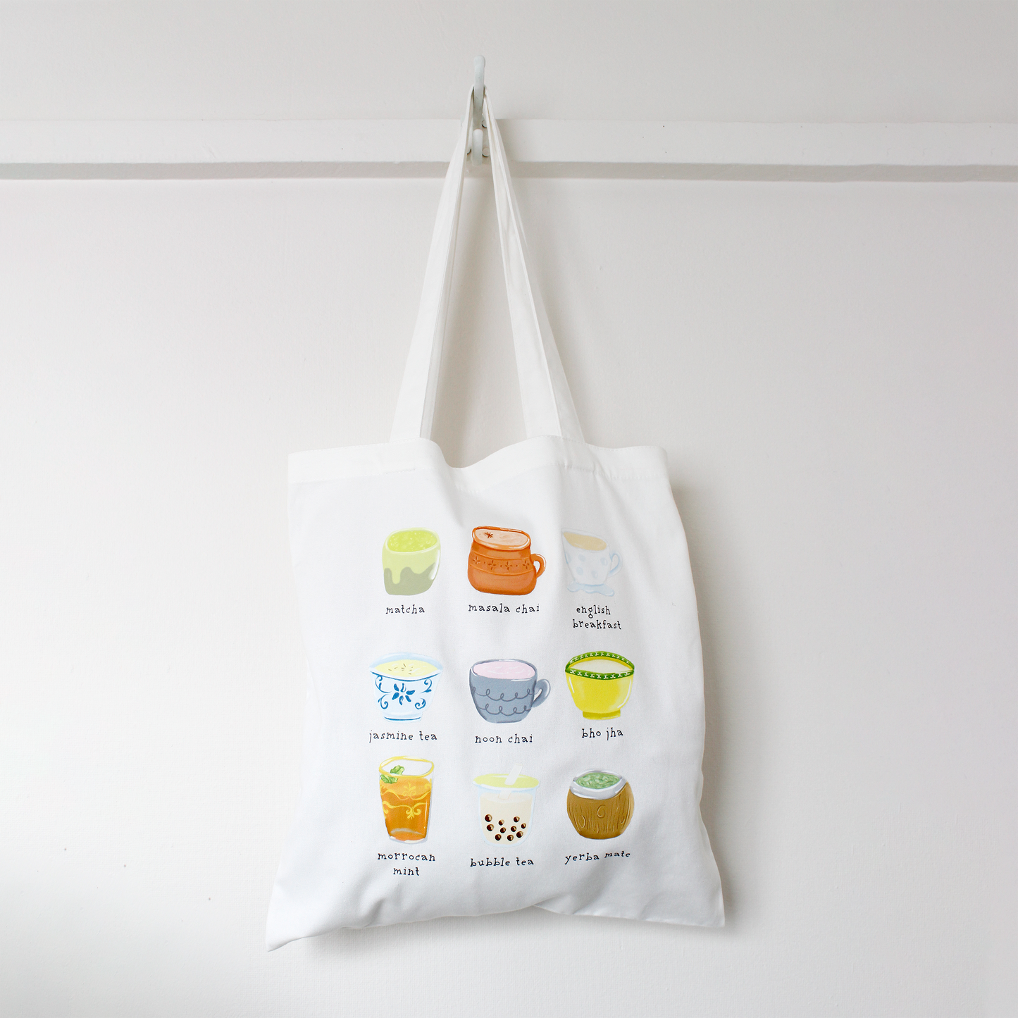 Tote bag with colorful illustrations of various teas from around the world on a white background